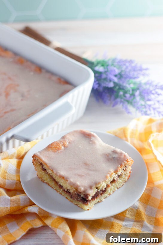 Easy Honey Bun Cake recipe made with yellow cake mix, sour cream, and chopped pecans is a Southern-inspired dessert that tastes just like a warm bakery honey bun! Perfectly moist, swirled with brown sugar and cinnamon, and topped with a sweet glaze, this easy doctored cake mix recipe comes together in minutes — no fancy baking skills required.