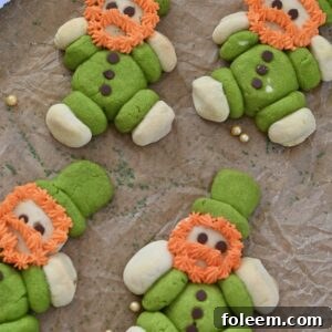 Lucky Leprechaun Cookies made with green and white sugar cookie dough, mini chocolate chip buttons, and fluffy orange frosting beards for St. Patrick's Day
