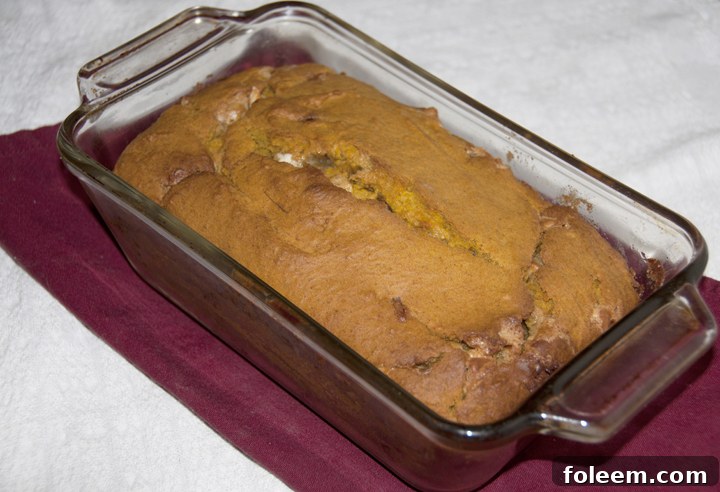 Delicious White Chocolate Pumpkin Bread with a slice on a cutting board, perfect for cozy fall evenings.