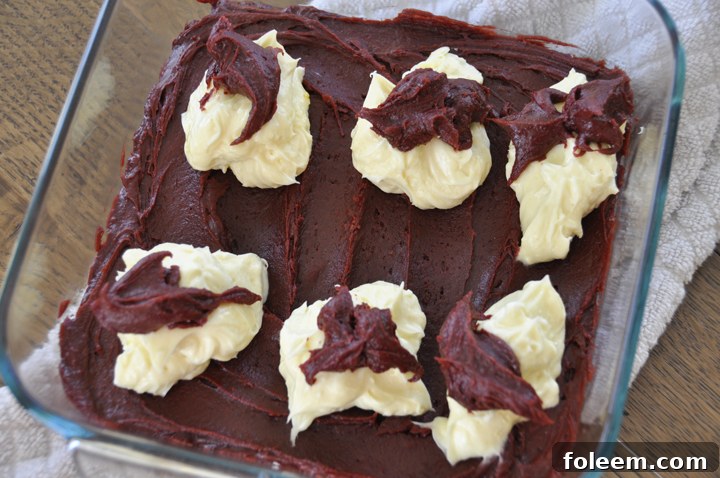 Before baking, Red Velvet Brownie batter with dollops of cheesecake mixture, ready for swirling.