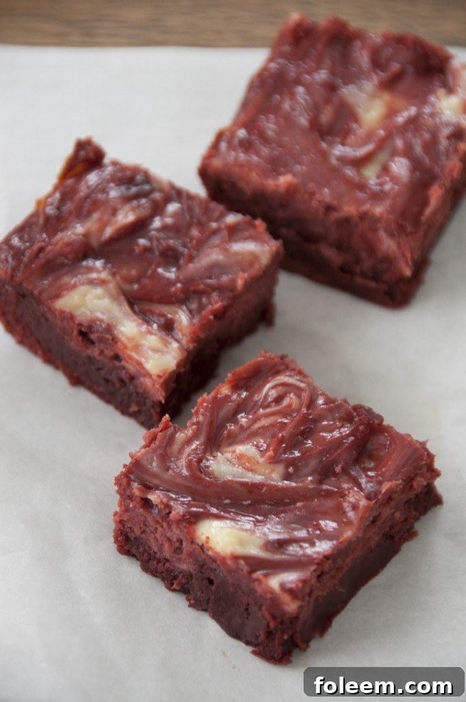 Deliciously baked Red Velvet Cheesecake Swirl Brownies cut into squares, ready to be served.