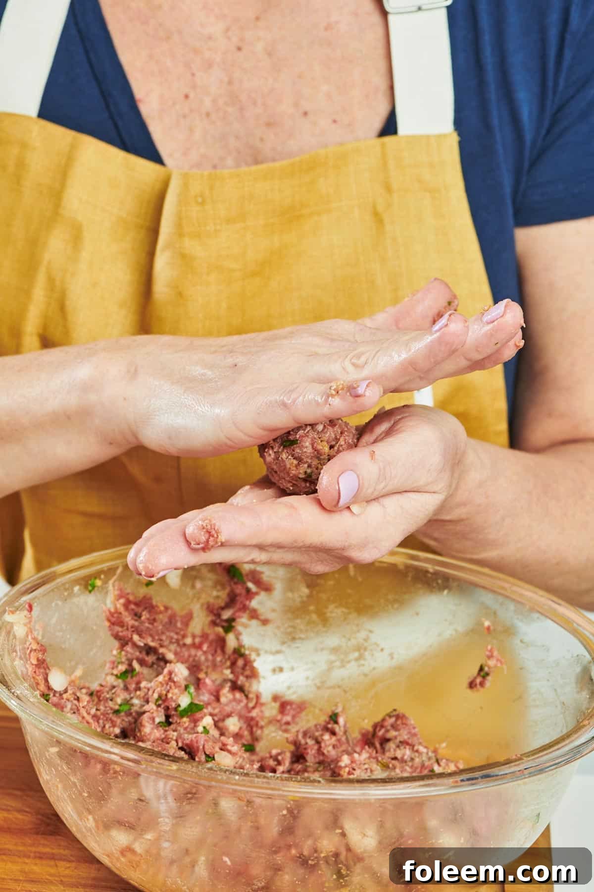 Woman shaping meatballs by hand.