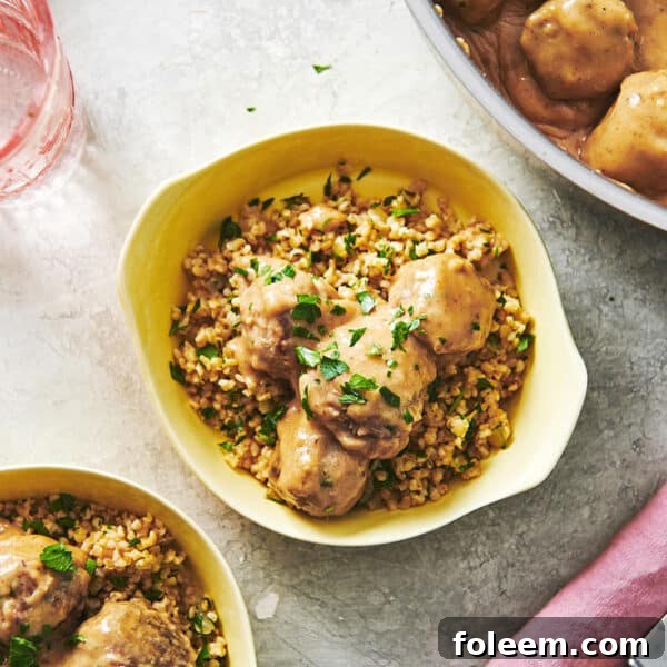 Swedish Meatballs in yellow bowls with fresh herbs on table.