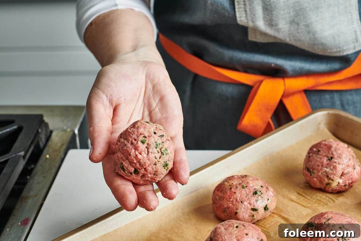 Woman showing off hand-formed meatballs.