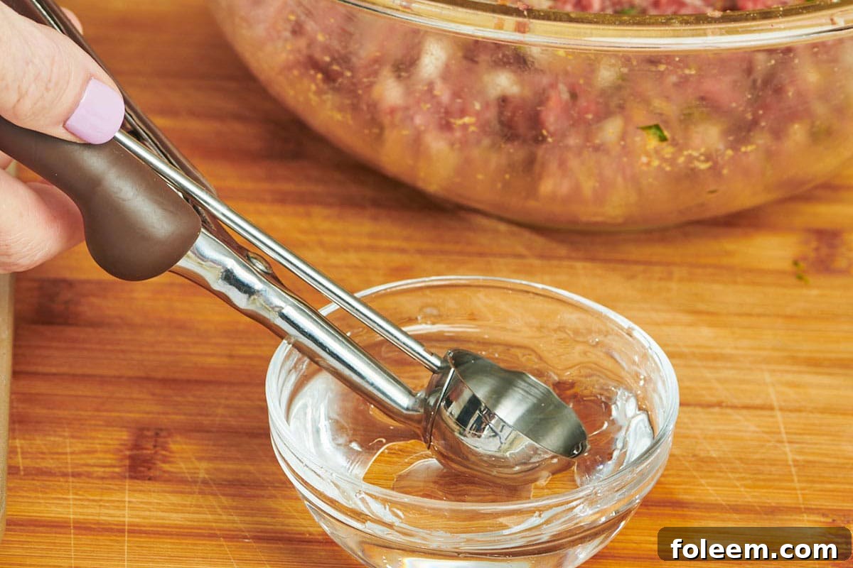 Dipping scoop into water to form meatballs.
