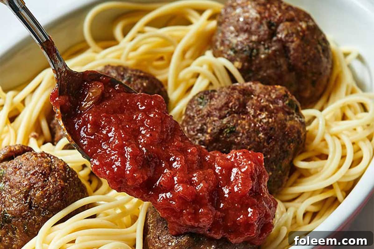 Spreading a platter of Jumbo Meatballs and spaghetti with marinara sauce.