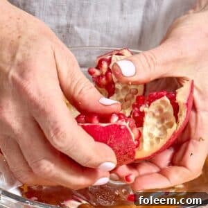 Woman peeling open fresh pomegranate.