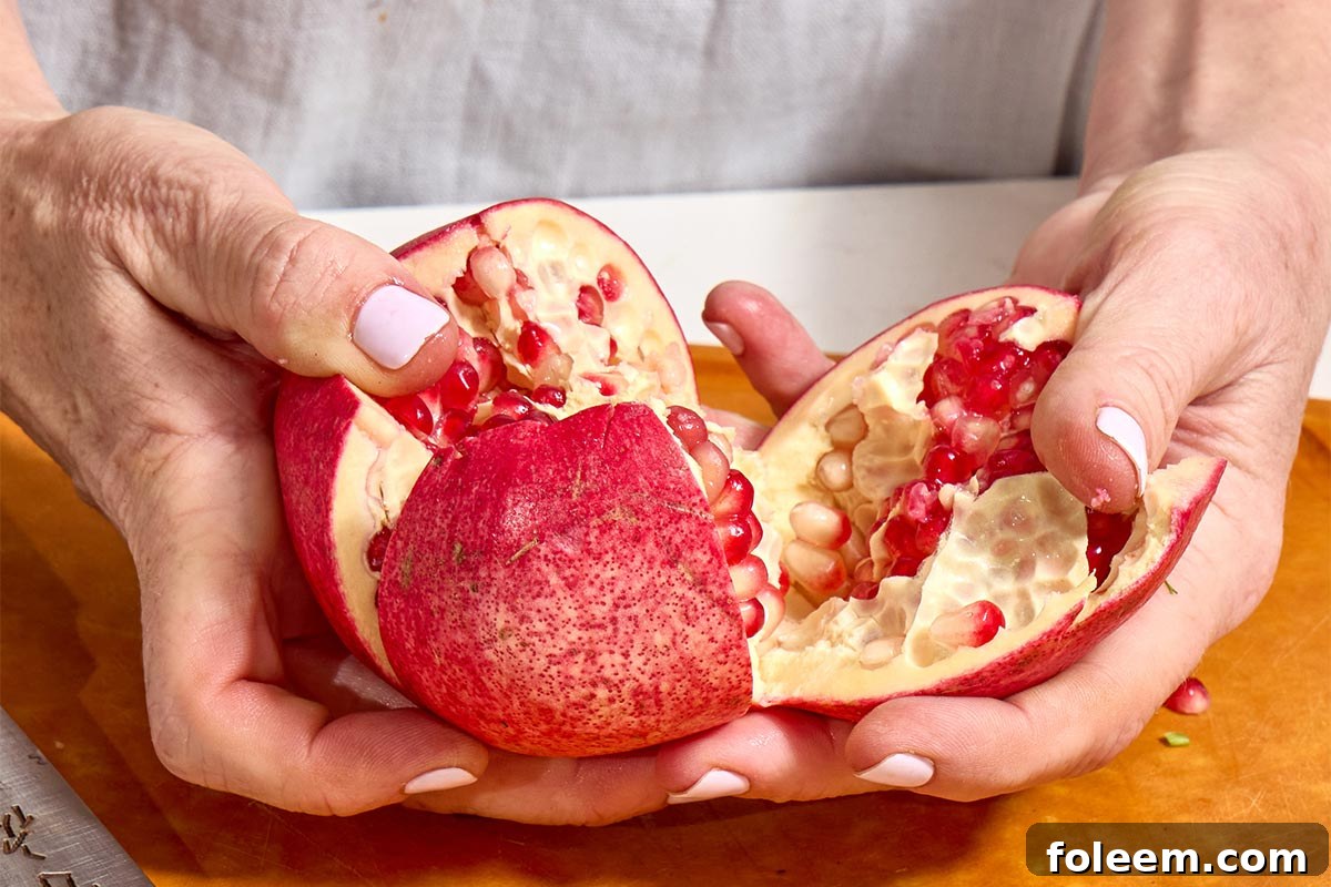 Woman prying open a sliced pomegranate.