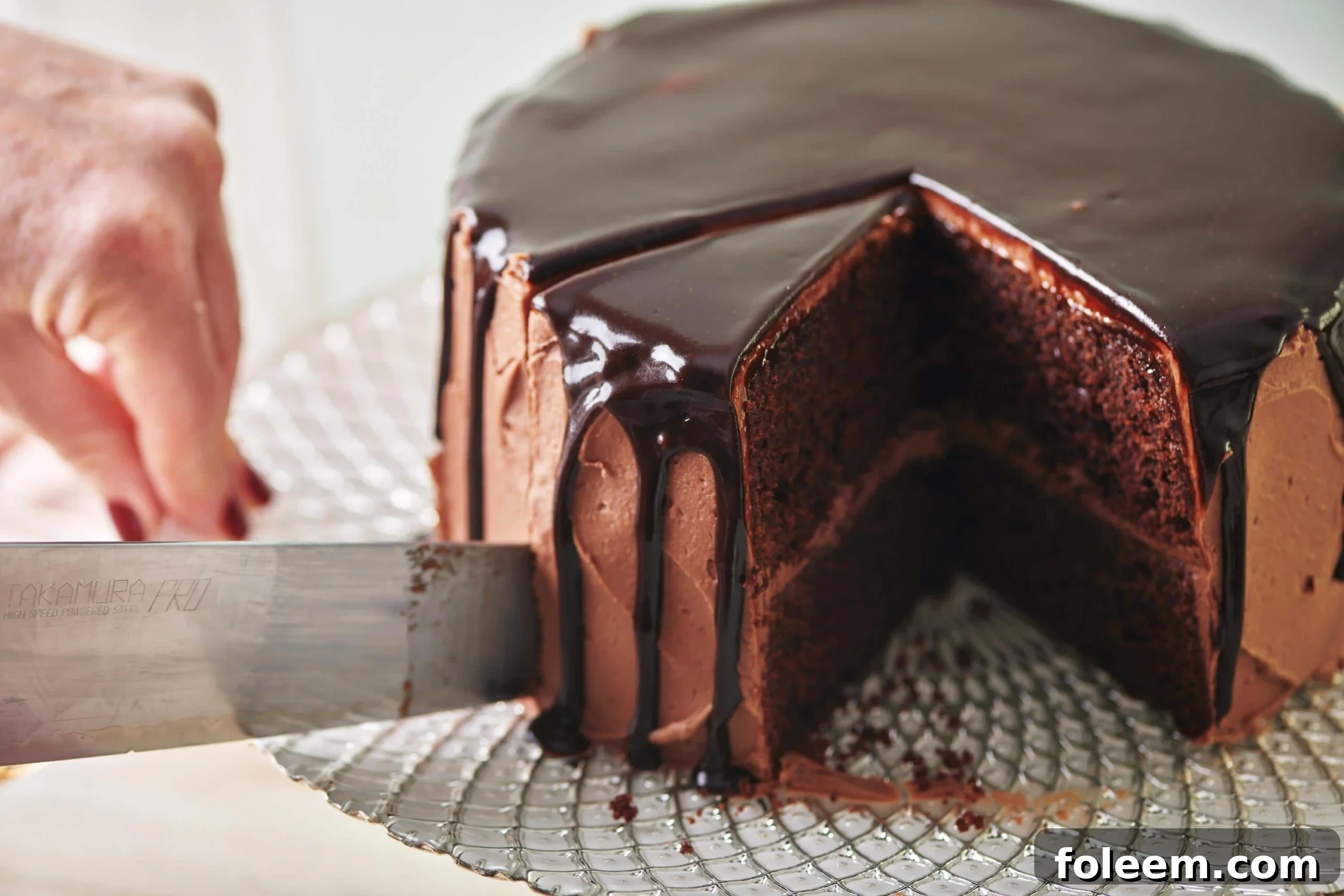 Woman slicing Devil's Food Cake on glass platter.