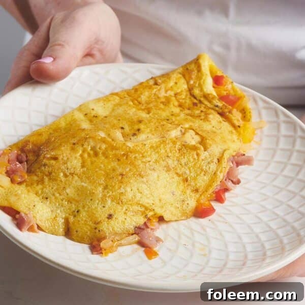 Woman holding a plate with a Denver Omelet.