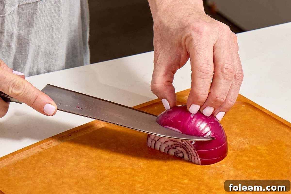 Woman cutting red onion slices with knife.