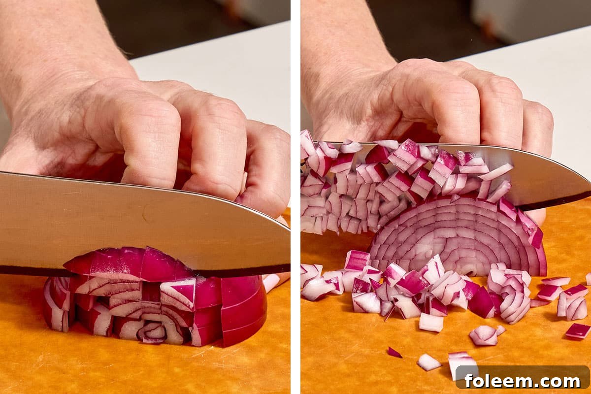 Woman dicing red onion strips on cutting board.