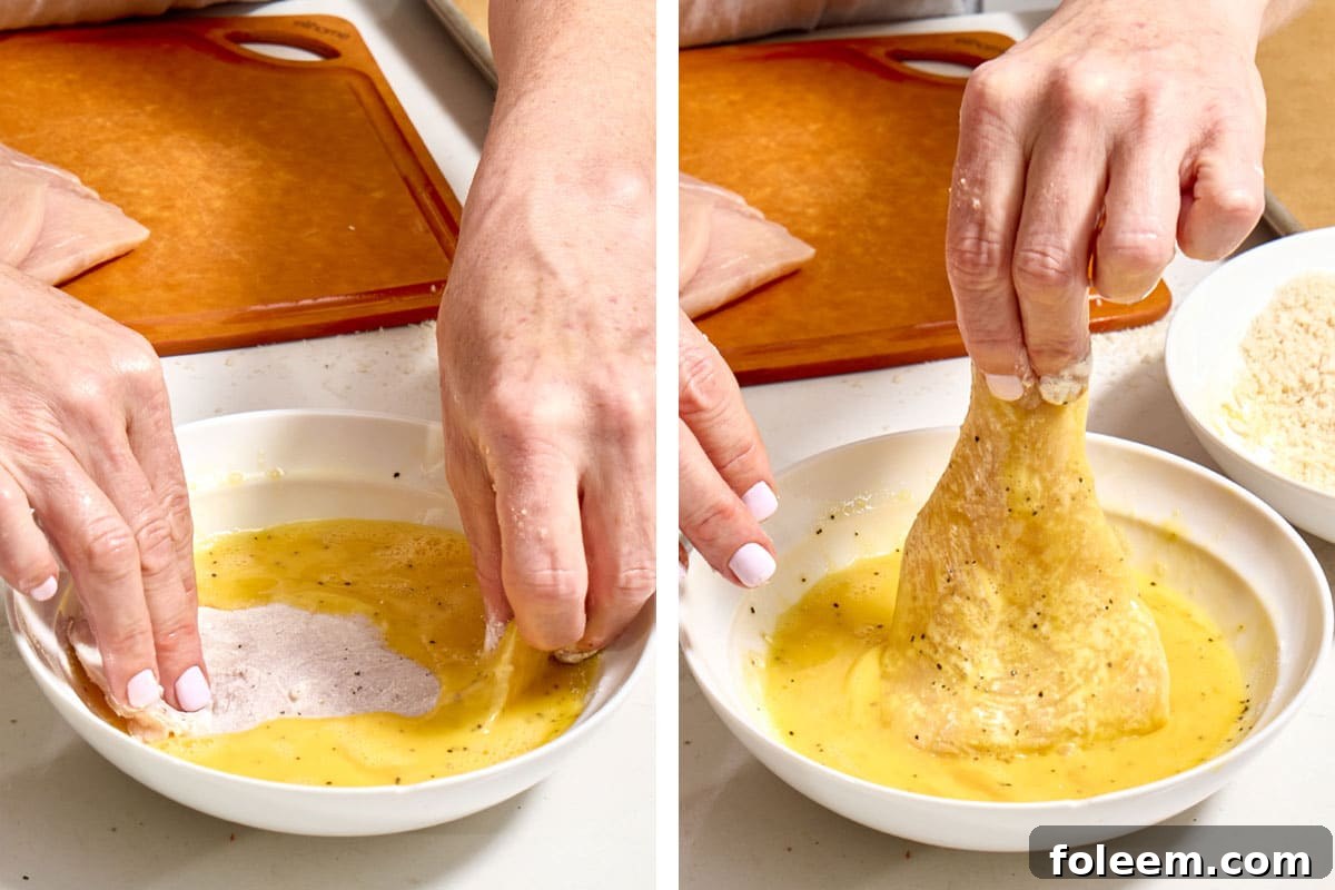 Woman dipping floured chicken into bowl of beaten eggs.