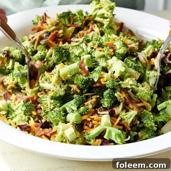 Two spoons in a bowl of Broccoli Salad.