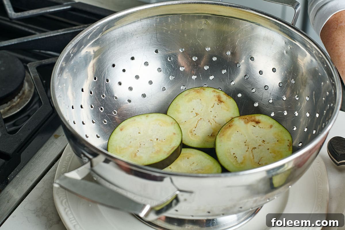 Rinsed eggplant slices in colander.