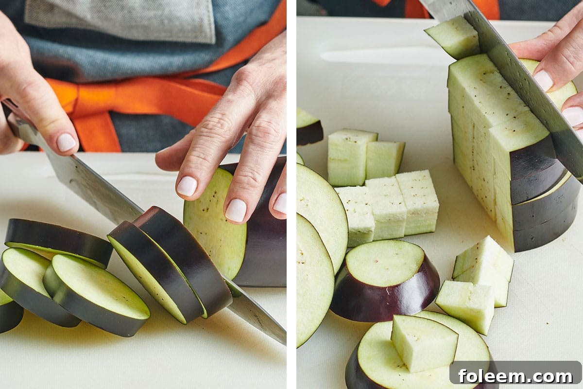Woman slicing and cubing fresh eggplant on cutting board with knife.