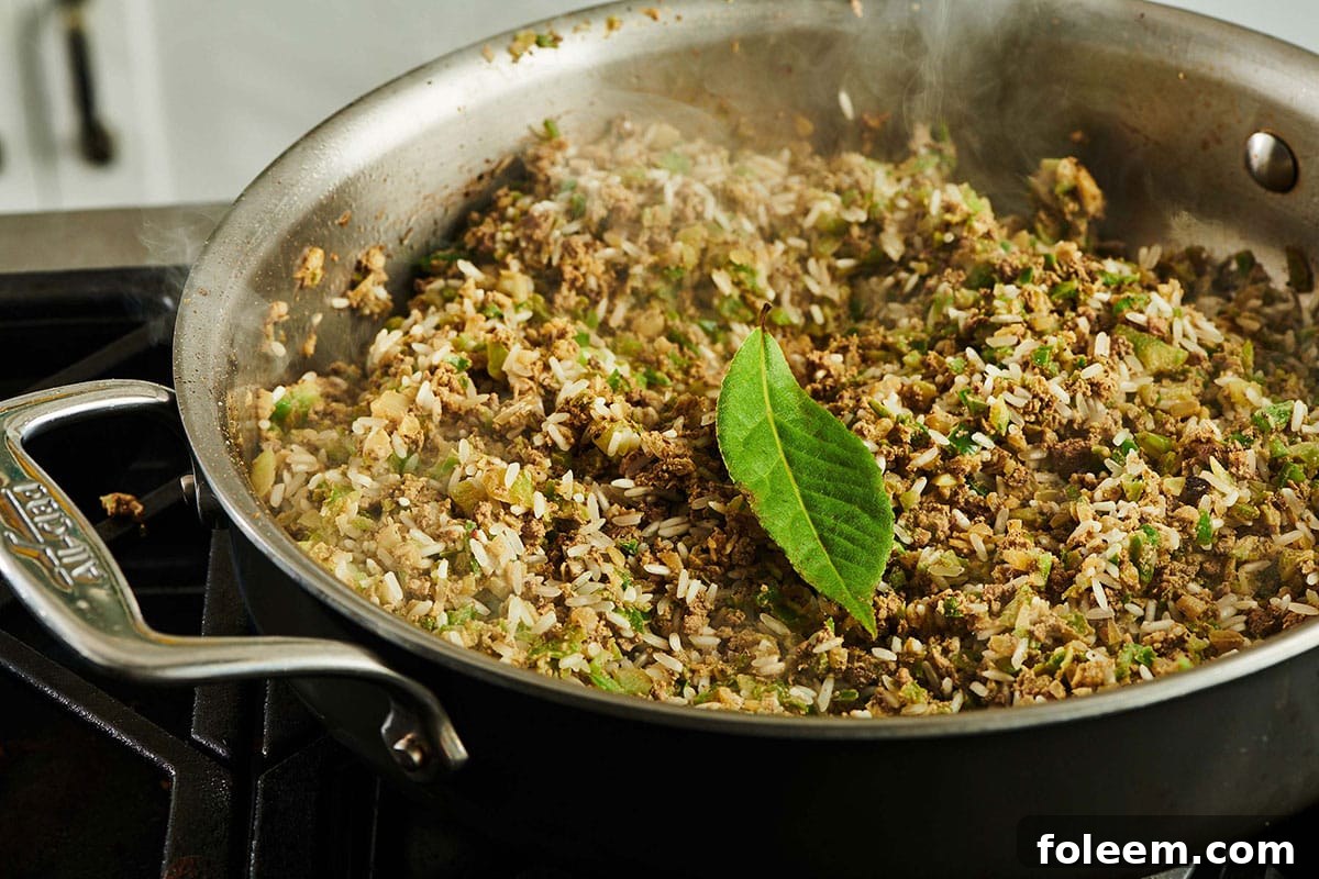 Bay leaf in pan of cooking dirty rice on stove.