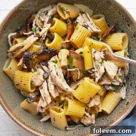 Simple chicken and pasta dish with Marsala wine sauce in brown bowl on table.