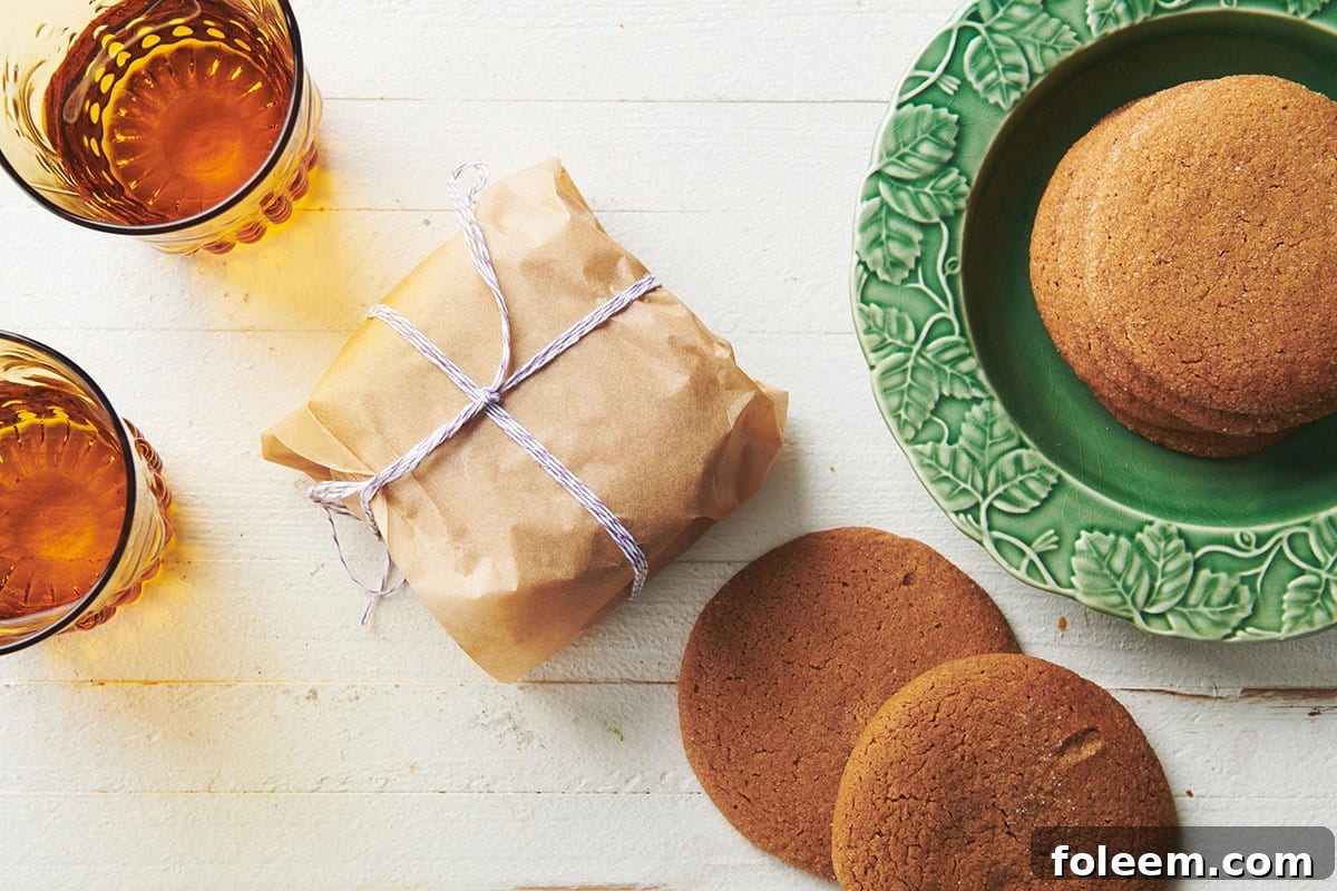 Table with gingersnaps on green plate and wrapped in parchment next to drinks.