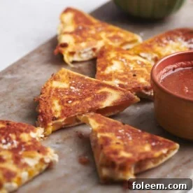 Cut Rotisserie Chicken and Cheese Quesadillas on a board with bowls of dip.