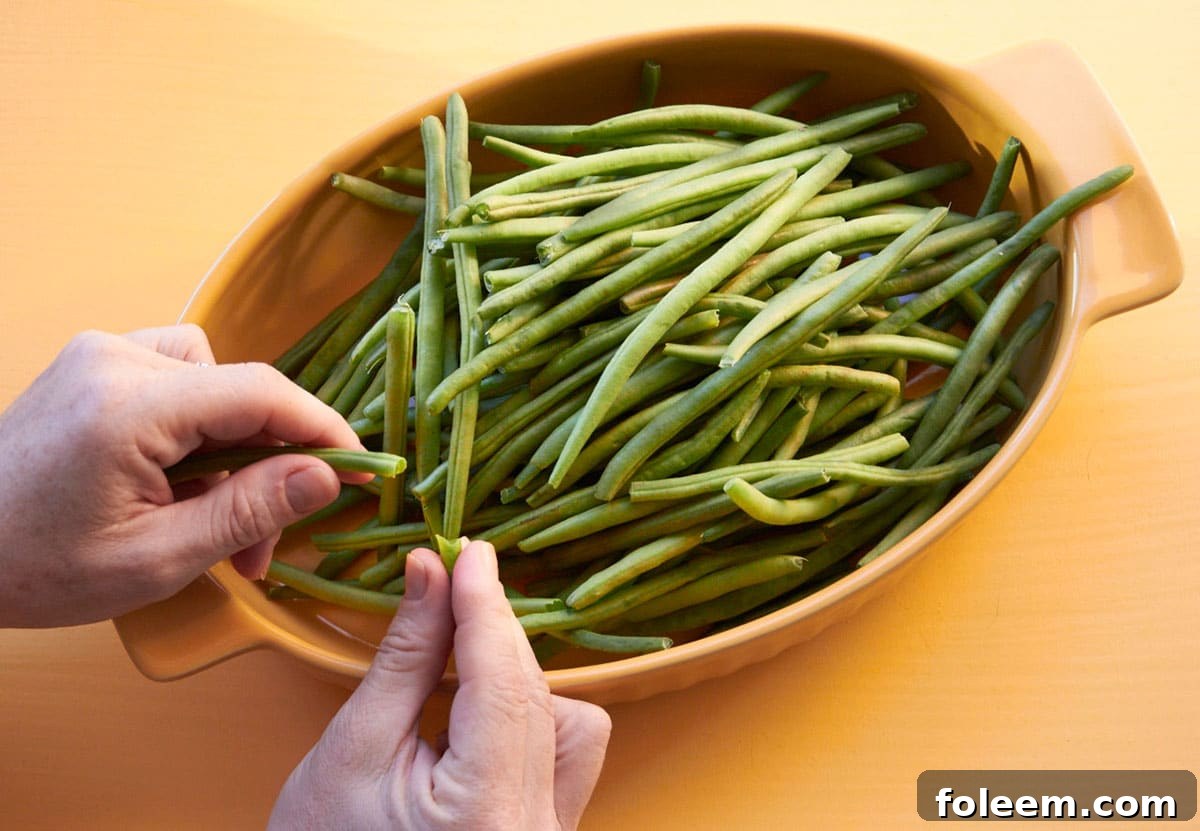 Katie Workman trimming fresh green beans over large yellow bowl.