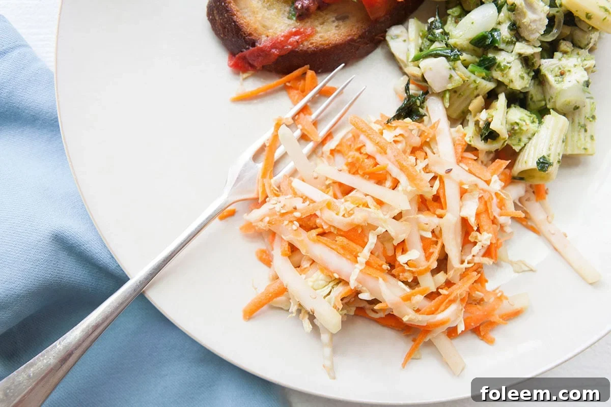 Carrot, Cabbage and Kohlrabi Slaw on plate with other dishes.