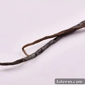 Two whole vanilla beans on table.