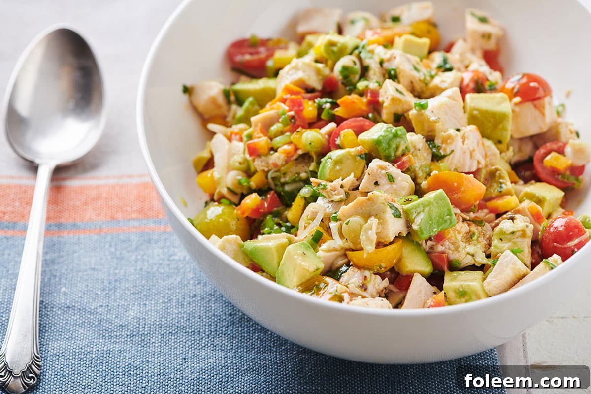 Chicken and Avocado Salad in white bowl next to spoon.