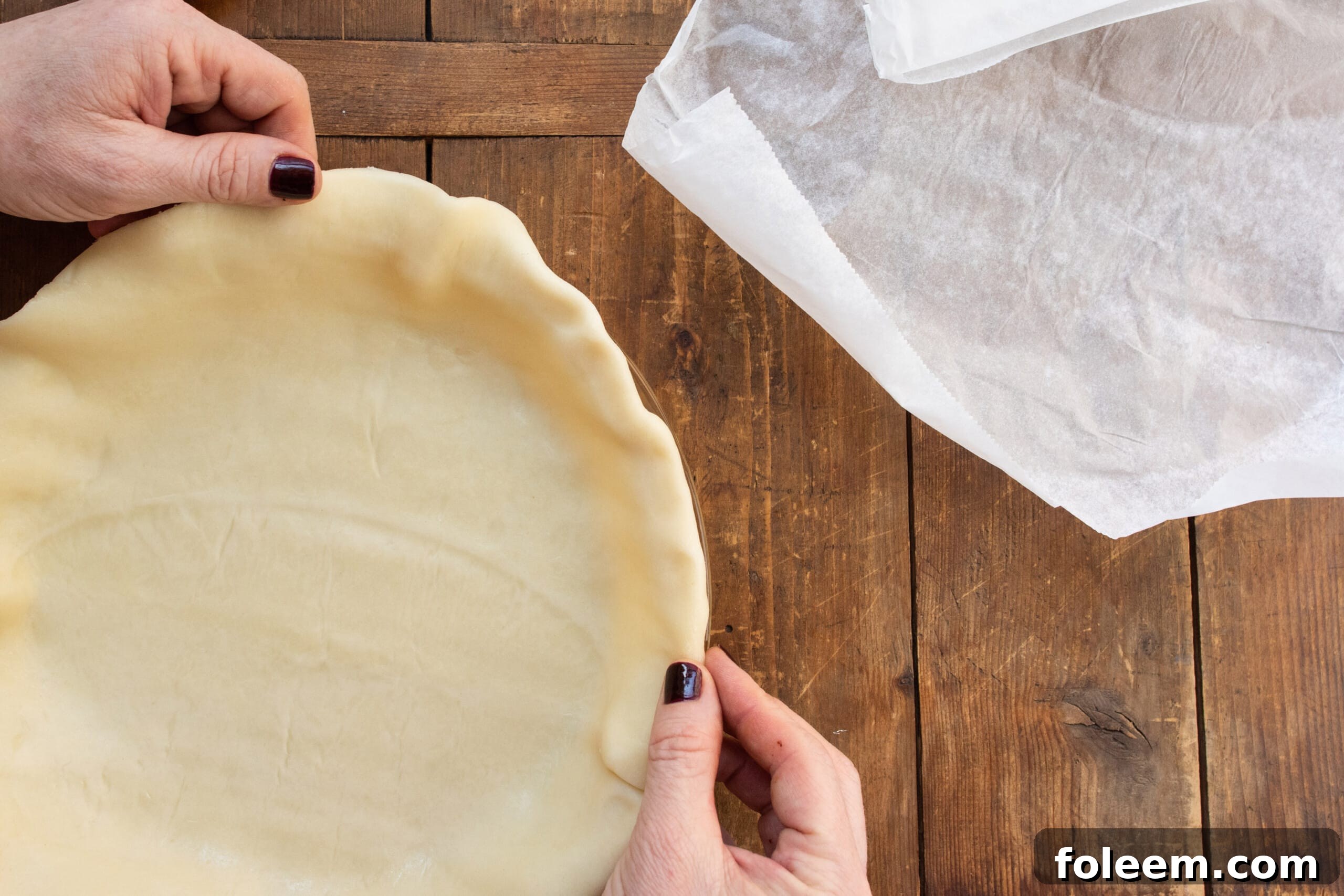 Woman molding the edges of a pie crust.