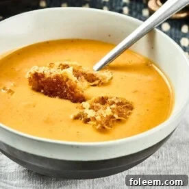 Pumpkin Curry Soup in white and black bowl on table.