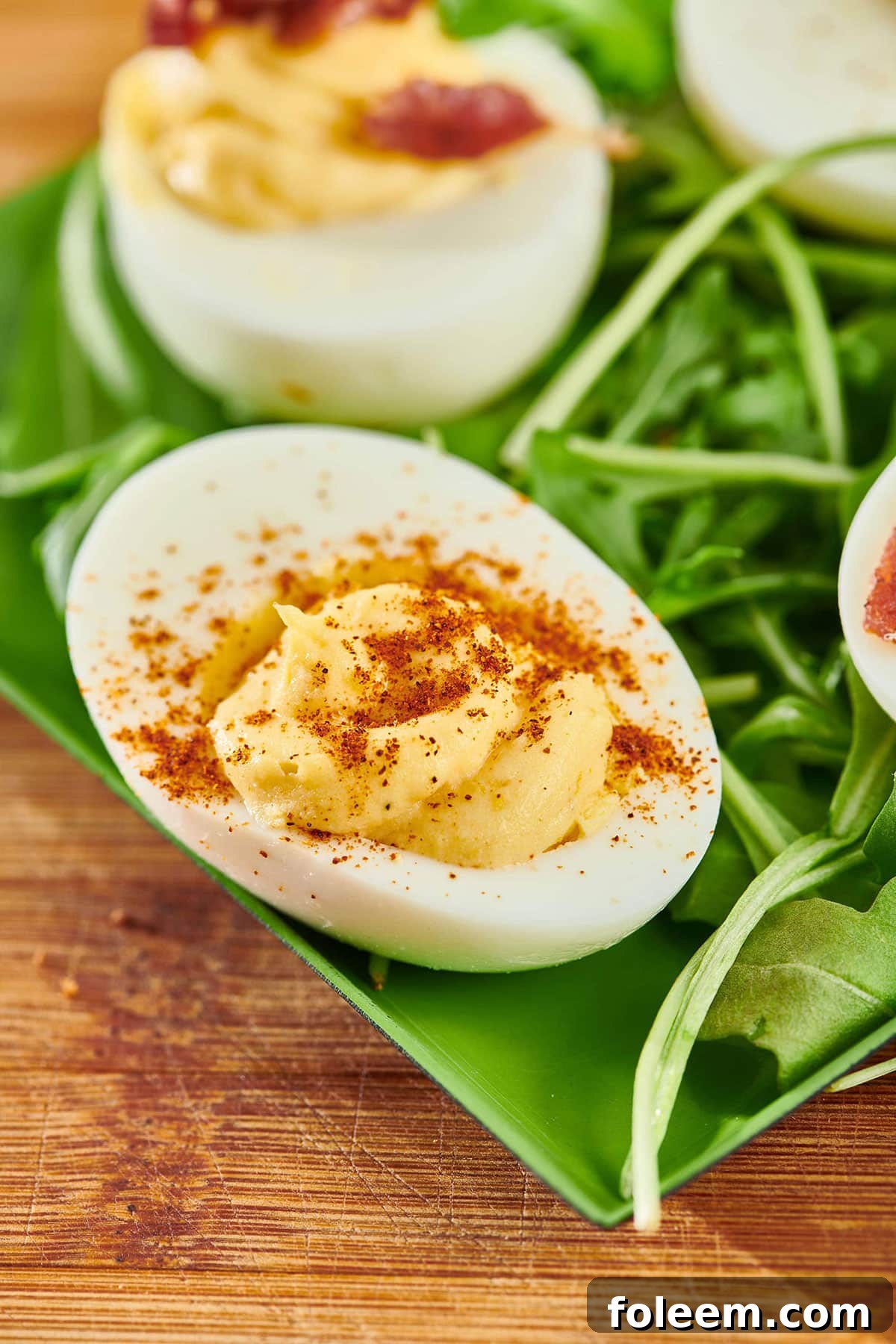 Two deviled eggs on green plate.