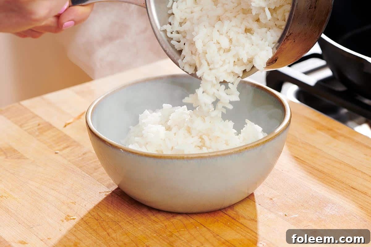 Pouring cooked white rice from pan into serving bowl.