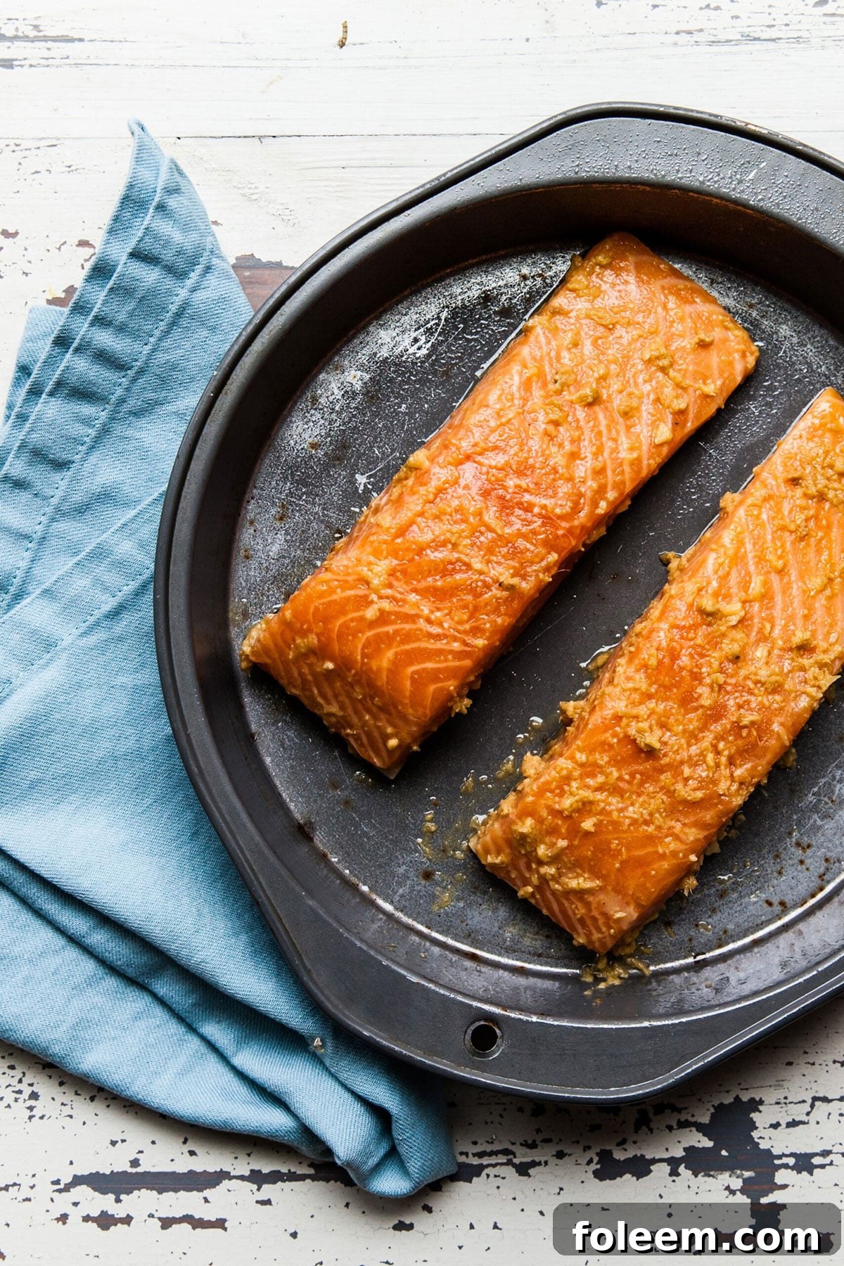 Baked salmon filets with Thai-inspired marinade on baking pan with blue napkin.