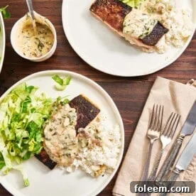 Plates of rice, salad, and salmon topped with creamy Tuscan sauce.