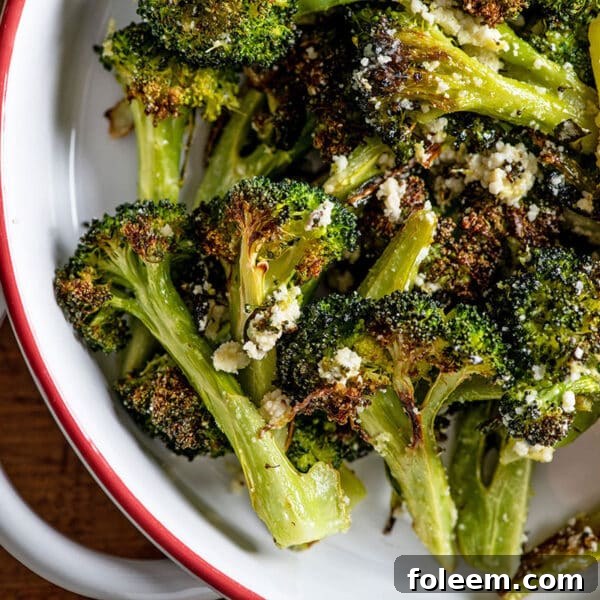 Roasted broccoli with Parmesan in white serving dish.