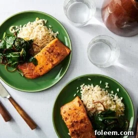 Two green plates with teriyaki salmon, greens, and rice.