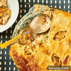 Spoon with turkey pot pie on table with plates.