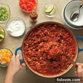 Serving turkey chili from pot next to chili toppings.