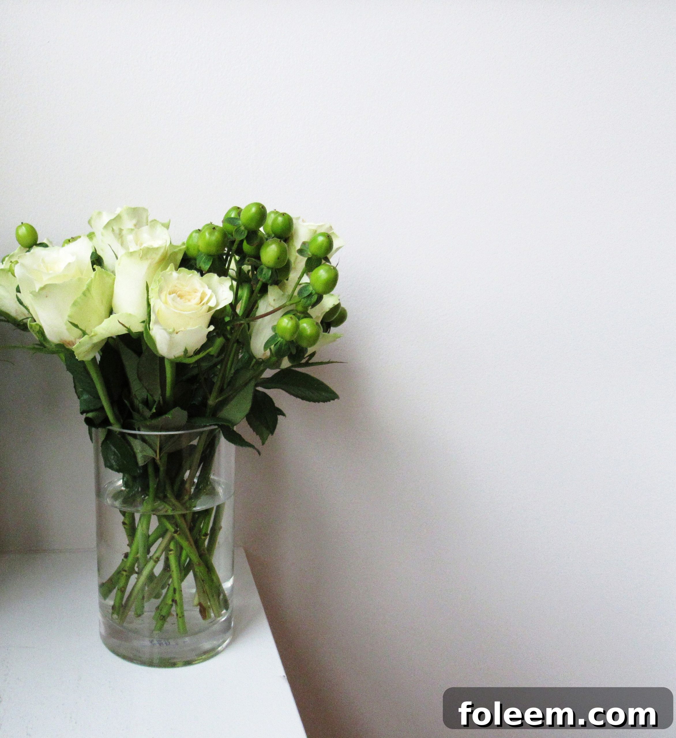 White flowers in glass vase on table.