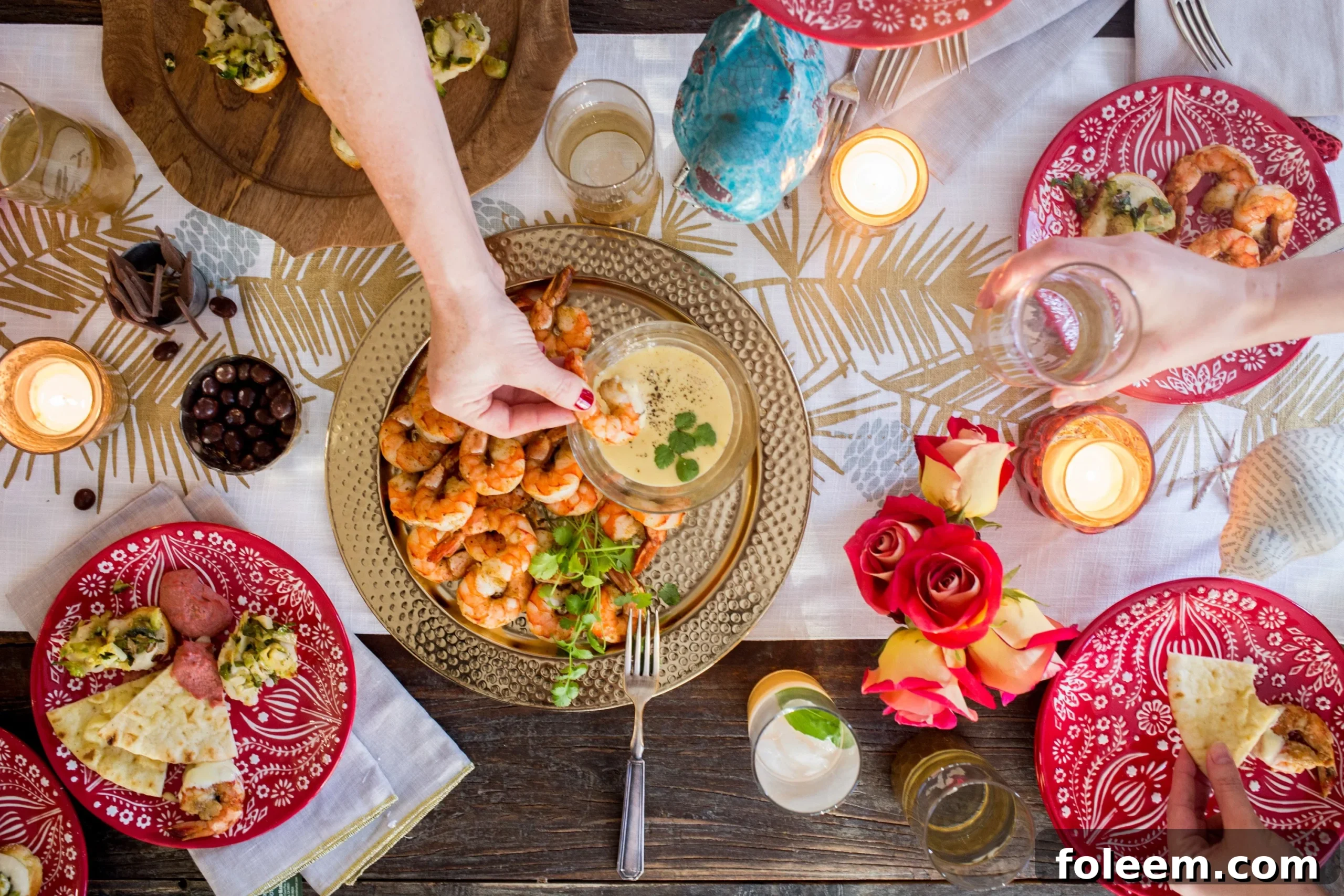 Woman dipping shrimp into sauce on festive holiday table.