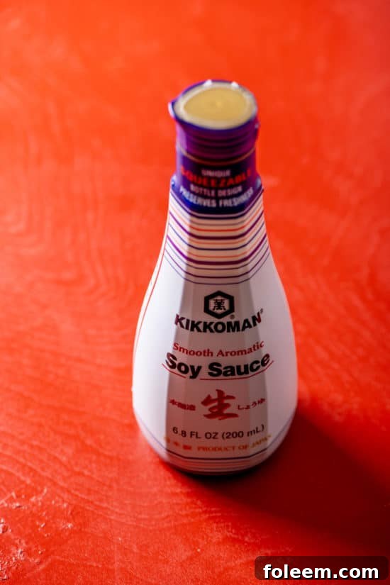 Jar of Kikkoman Soy Sauce on red table.