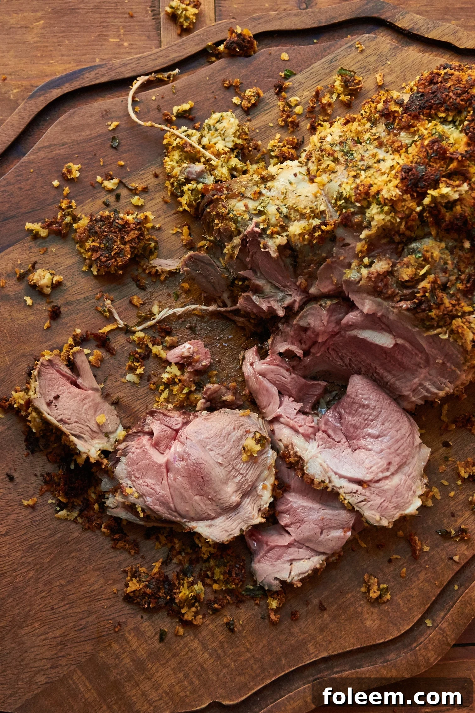 Herbed Boneless Leg of Lamb with Mustard Crust on a wooden platter.