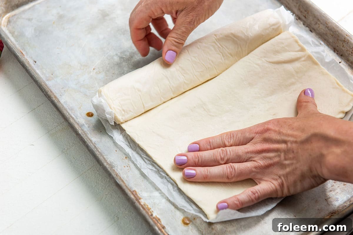 Woman unrolling puff pastry dough.