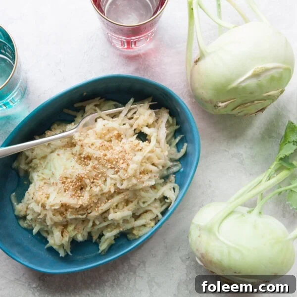 Dish of Asian Kohlrabi and Apple Slaw on a table next to whole kohlrabies.