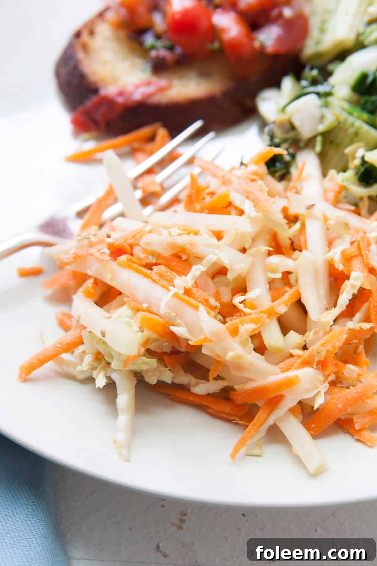 Carrot, Cabbage, and Kohlrabi Slaw with Miso Dressing  on white plate with blue napkin.