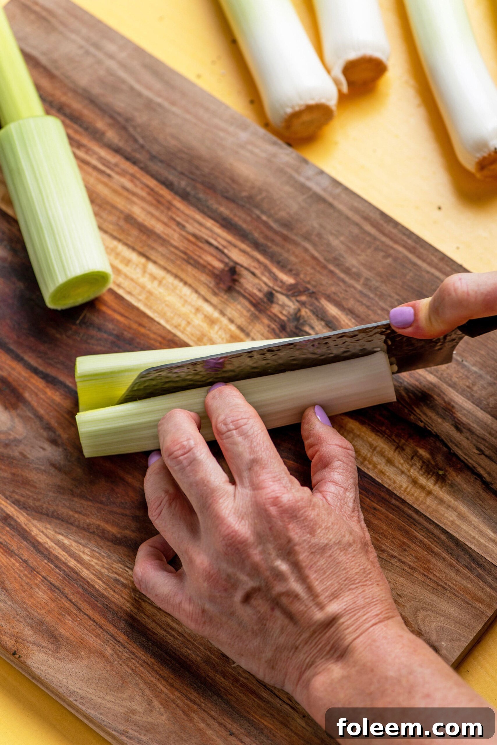 Woman slicing leeks on a cutting board.