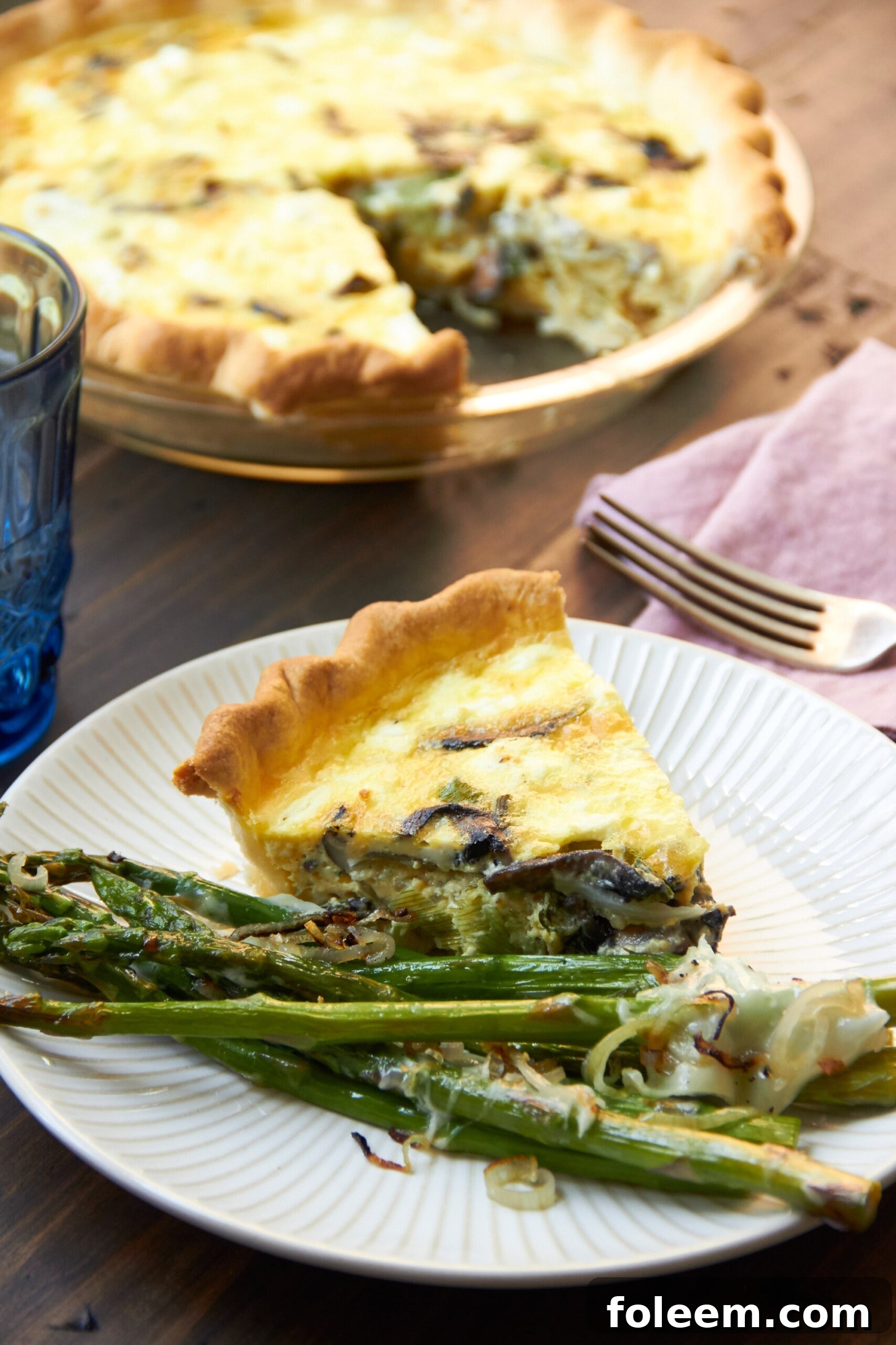 Leek, Mushroom, and Goat Cheese Quiche on a plate with asparagus.