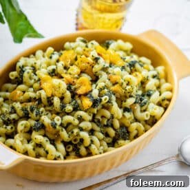 Cavatappi with Roasted Cherry Tomatoes and Pesto in yellow serving dish on table.