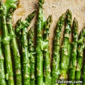Roasted Asparagus on parchment paper and topped with Pesto Crème Fraiche.