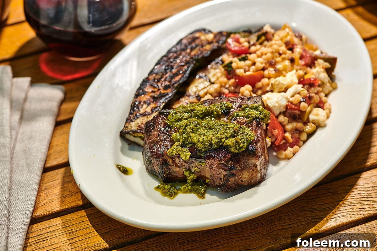 Grilled loin lamb chop on plate with mint and basil pesto and grilled sides.